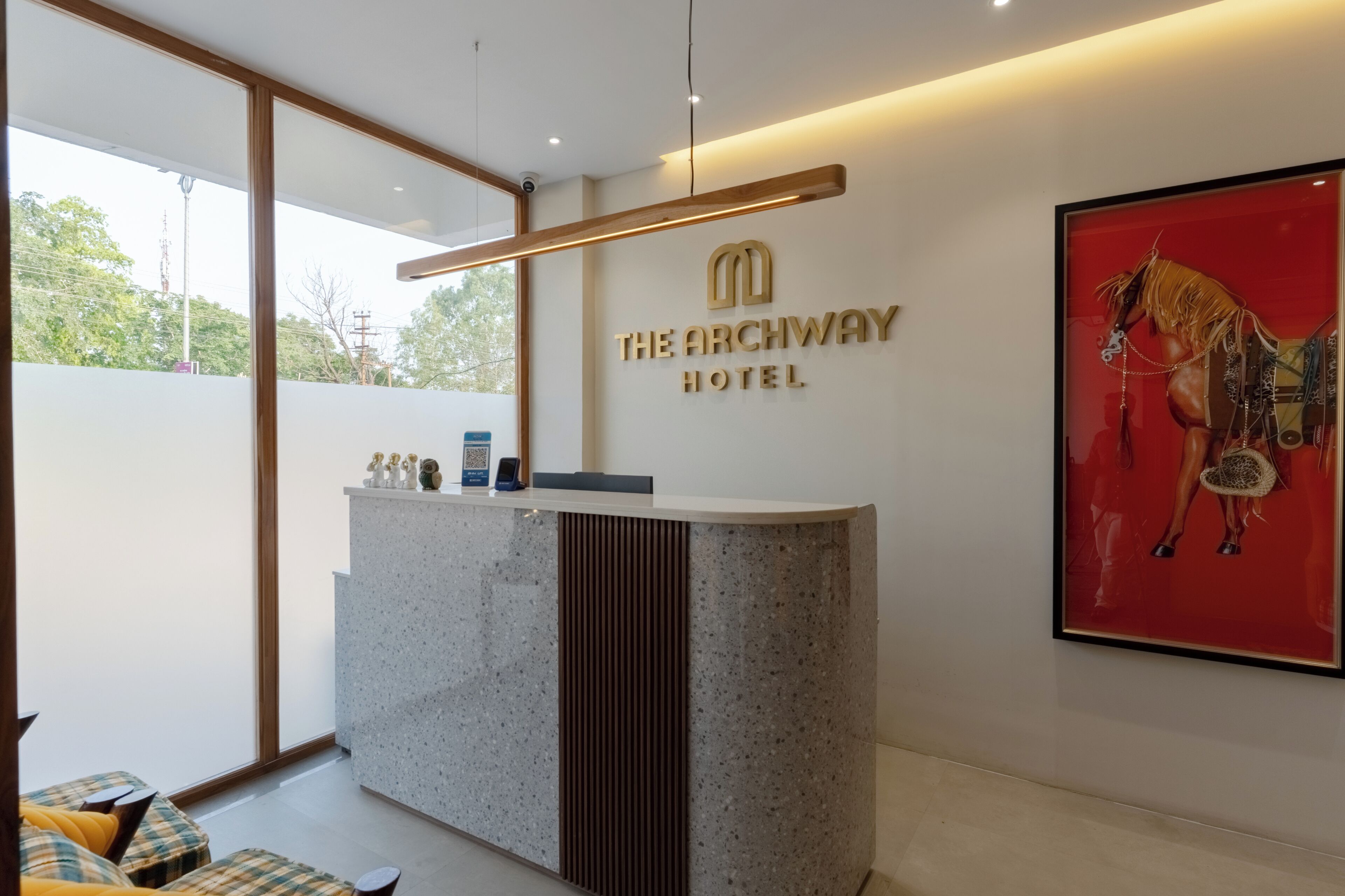A reception desk with a modern design, a mounted sign for The Archway Hotel, and a framed artwork of a horse on the wall.