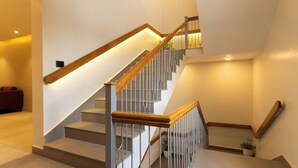 A staircase with wooden handrails and metal balusters, leading to an upper floor. - The Archway Hotel (Haldwani)