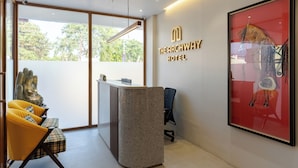 A reception desk with a modern design, a Buddha statue, and a framed artwork on the wall. - The Archway Hotel (Haldwani)