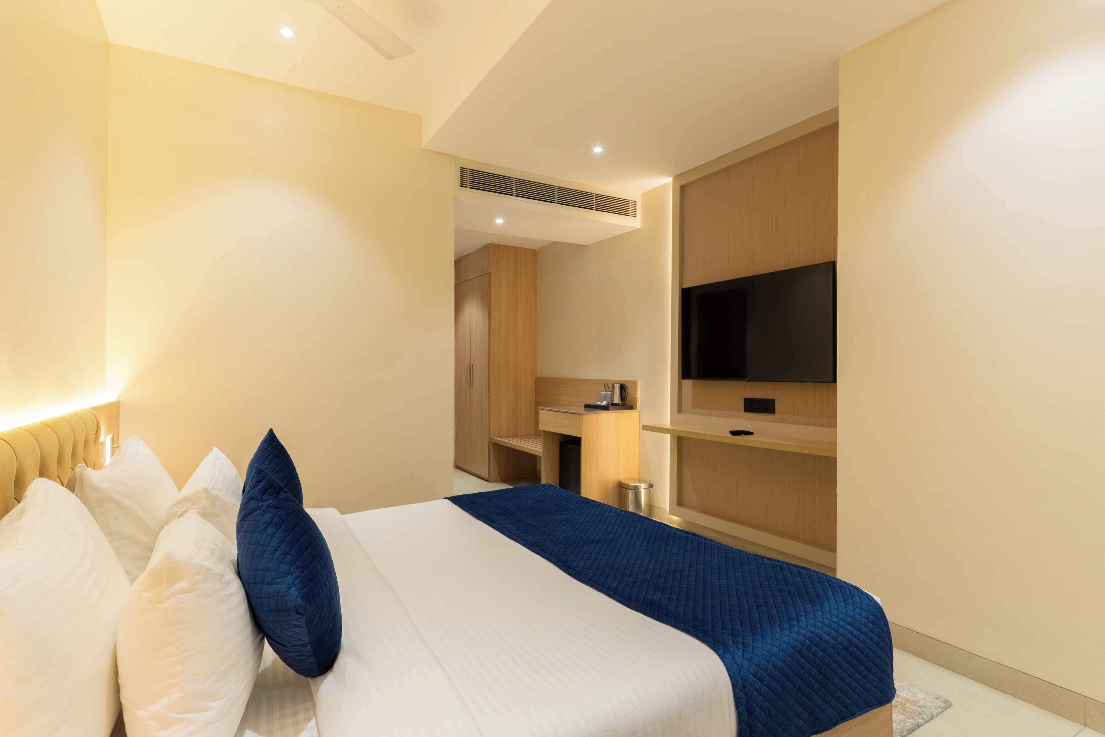 Una habitación de hotel con una cama, televisión, escritorio y kitchenette.