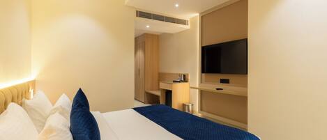 Una habitación de hotel con una cama, televisión, escritorio y kitchenette.