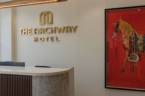 Una recepción con el logotipo de 'The Archway Hotel' y una obra de arte enmarcada de un caballo.