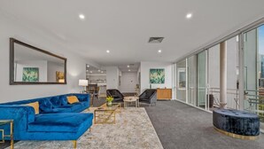 A modern living room with a blue sofa, a coffee table, and a large mirror. - Exclusive Stays - Southgate (Southbank)