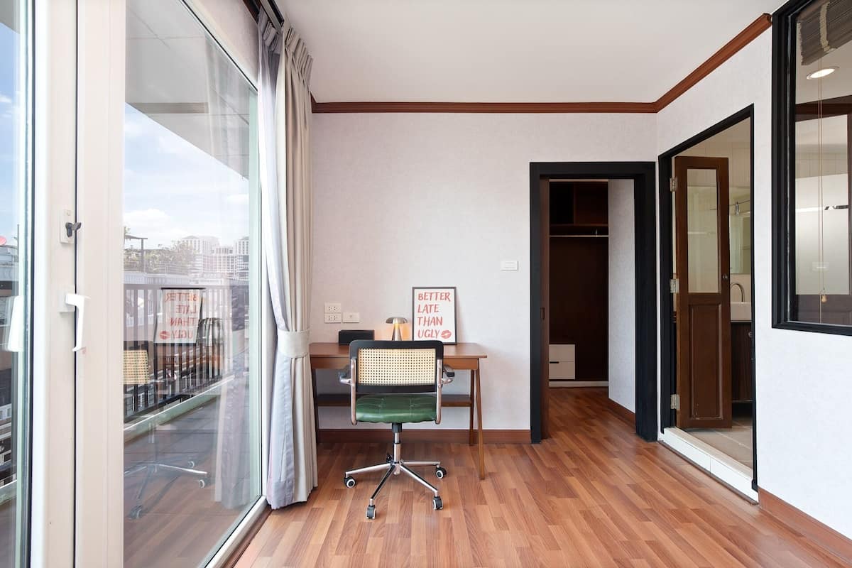 Ein Zimmer mit Schreibtisch, Stuhl und Blick auf die Stadt durch ein großes Fenster.