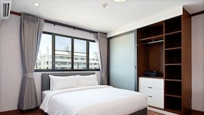 A bedroom with a bed, a window, a wardrobe, and a view of buildings outside. - Capitel Ekkamai Hotel (Bangkok)