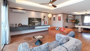 A modern living room with a sofa, a coffee table, a TV, and a ceiling fan. - Capitel Ekkamai Hotel (Bangkok)
