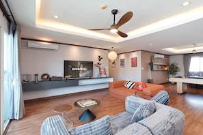 A modern living room with a sofa, a coffee table, a TV, and a ceiling fan.