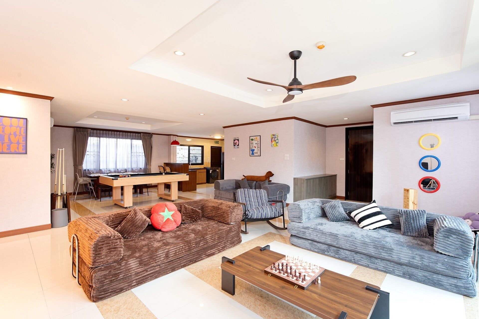 A modern living room with a pool table, sofas, a coffee table, and a ceiling fan.