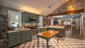 Une cuisine avec un carrelage à motifs, des placards verts et une table en bois.