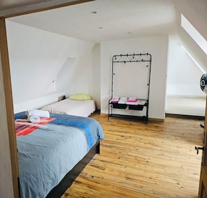 Ein Schlafzimmer mit Bett, Holzboden, einem schwarzen Metallhandtuchhalter und einem Oberlicht.