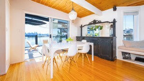Un espace de restauration moderne avec une table et des chaises blanches, un plafond en bois et une vue sur la ville grâce à de grandes fenêtres.