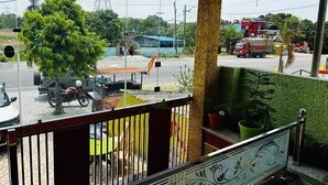 Un balcon donnant sur une rue, un arbre et un bâtiment en arrière-plan.