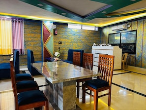 A dining area with a marble table, wooden chairs, and a blue sofa.