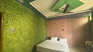 Une chambre à coucher avec un lit, un ventilateur de plafond et un mur vert à texture.