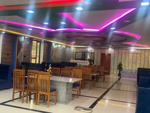 A restaurant with wooden chairs, a marble table, and a modern ceiling design.