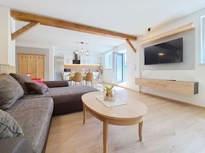 A modern living room with a sofa, a coffee table, and a TV mounted on the wall. - Halbeis by Interhome (Matrei am Brenner)