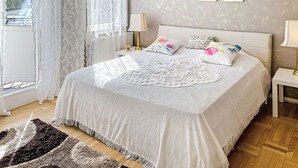 Un dormitorio con cama, mesita de noche, lámpara, ventana con cortinas y decoración en la pared.