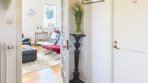 Un umbral que da a una sala de estar con un sofá, una mesa de centro, una lámpara y un jarrón con flores.