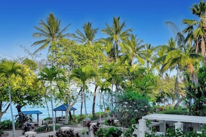 Un resort tropical con palmeras, un pabellón y vistas al océano.