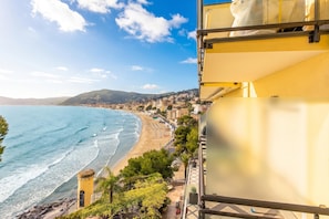 A coastal view with a beach, ocean, and a building with balconies overlooking the sea. - Attico Giancardi (Alassio)