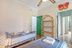 A bedroom with two beds, a bamboo shelf, and a butterfly decoration. - Attico Giancardi - Beachfront Sea-view Terrace (Alassio)