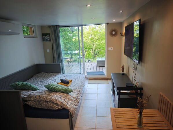 A modern bedroom with a bed, a desk, a TV, and a view of the outdoors. - Nature break in green Provence (Artigues)