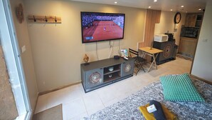 Ett vardagsrum med en tv, en soffa, ett litet bord och ett köksområde i bakgrunden.