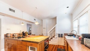 Cucina con mobili in legno, isola centrale, forno integrato e lavello in acciaio inossidabile.