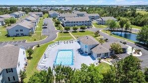 A residential area with a swimming pool, multiple houses, and a lake. - Gulf Shores Condo with Pool & Hot Tub (Gulf Shores)