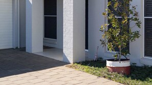 Een woonhuis met een verharde oprit, een garage en een bloempot.