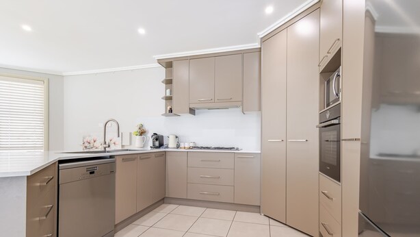 Een moderne keuken met een vaatwasser, fornuis, oven en een inbouwmagnetron.