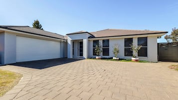 A two-story residential building with a paved driveway and potted plants.