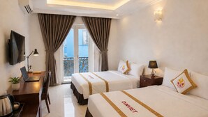 A hotel room with two beds, a desk with a laptop, a TV, and a balcony with curtains. - The Rice Hotel & Tour - 27 Nguyen Thai Binh (Ho Chi Minh City)