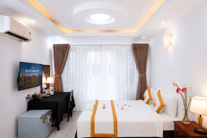A hotel room with a bed, desk, chair, and a television displaying a cityscape. - The Rice Hotel & Tour - 27 Nguyen Thai Binh (Ho Chi Minh City)