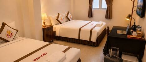 A hotel room with two beds, a desk with a laptop, a suitcase, and an air conditioning unit.