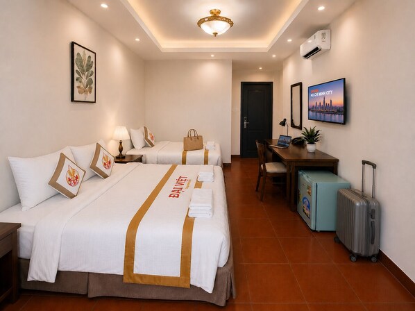 A hotel room with two beds, a desk, a chair, a TV, and a suitcase. - The Rice Hotel & Tour - 27 Nguyen Thai Binh (Ho Chi Minh City)