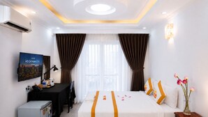 A hotel room with a bed, desk, TV, and a view of the city. - The Rice Hotel & Tour - 27 Nguyen Thai Binh (Ho Chi Minh City)
