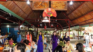 An indoor dining area with tables and chairs, a thatched roof, and hanging decorations. - The Rice Hotel & Tour - 27 Nguyen Thai Binh (Ho Chi Minh City)