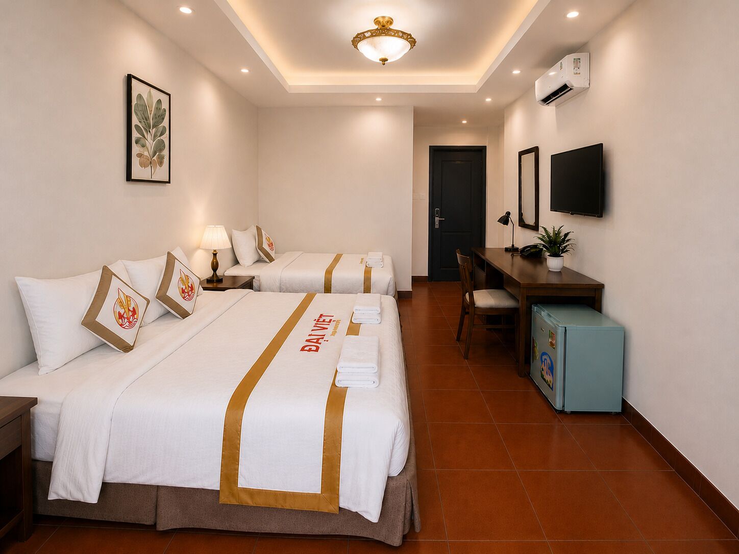 A hotel room with two beds, a desk, a chair, a TV, and a small cabinet.