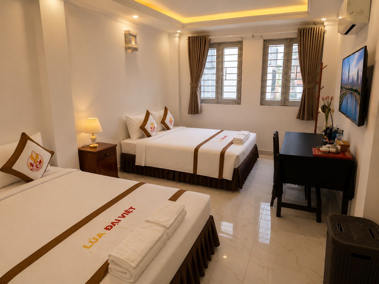 A hotel room with two beds, a desk, and a chair.