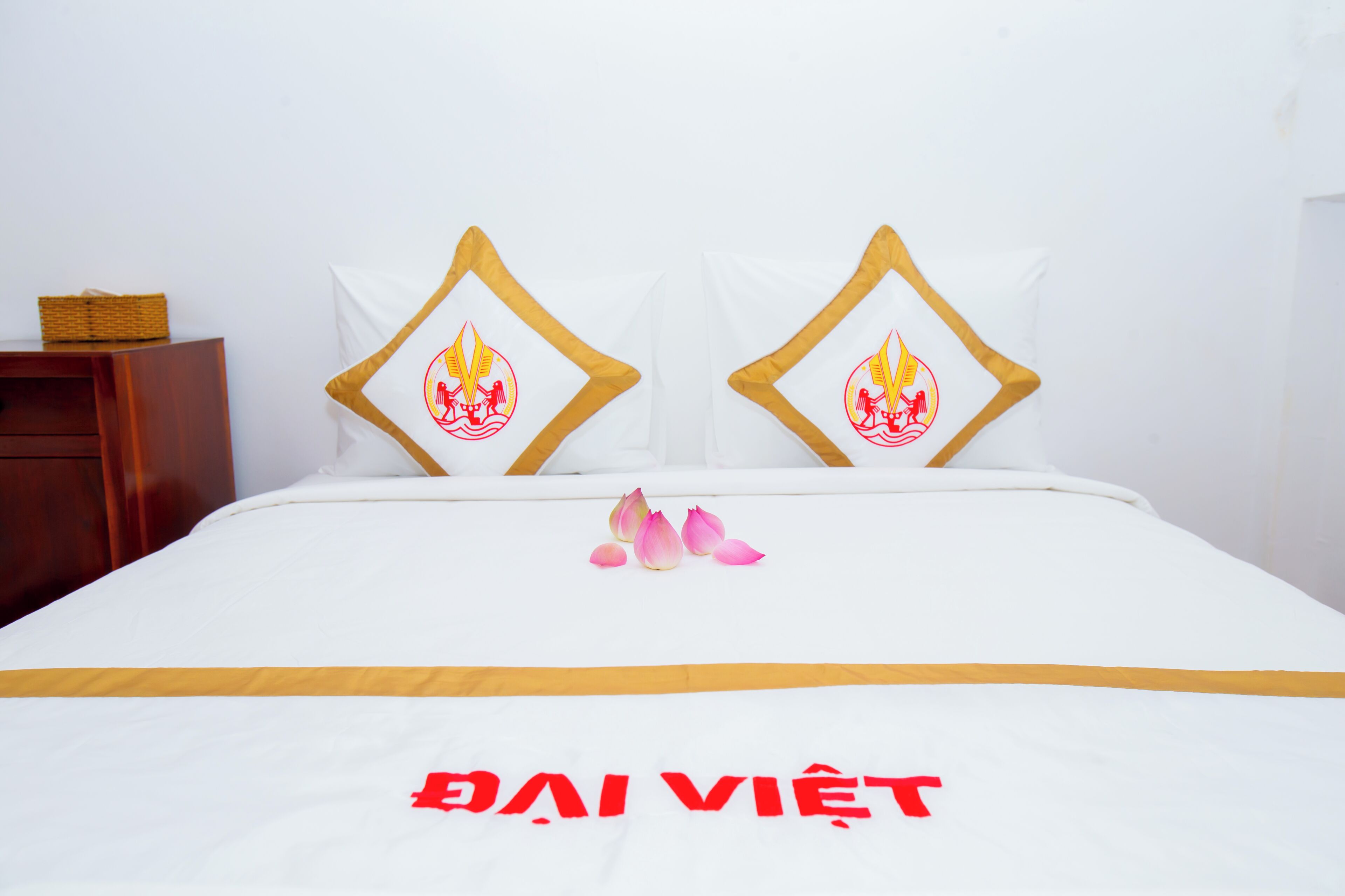 A hotel room with a bed, pillows with a flame design, and a bedspread with text.