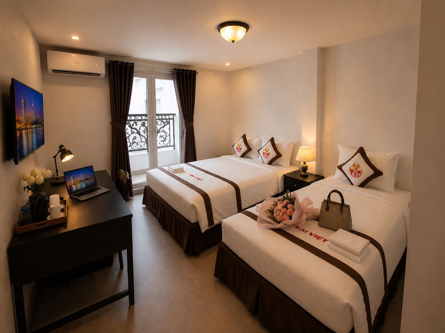 Une chambre d’hôtel avec deux lits, un bureau, un ordinateur portable, une télévision et un balcon avec des rideaux.