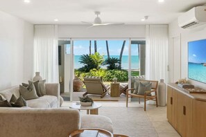 Ein modernes Wohnzimmer mit großem Fenster, Deckenventilator und Meerblick.