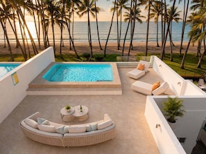 Ein Poolbereich mit Blick auf Strand und Palmen.