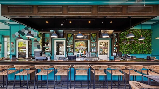 A bar area with a counter, bar stools, and a green wall with a sign. - Modern Villa Near Disney, Resort Splash Park (CHAMPIONS GT)