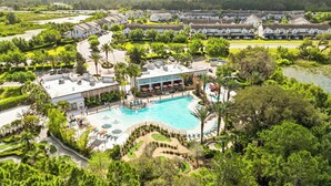 A resort with a swimming pool, a golf course, and a building with outdoor seating. - Modern Villa Near Disney, Resort Splash Park (CHAMPIONS GT)
