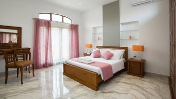 A bedroom with a bed, bedside tables, a desk, a chair, a mirror, and a window with curtains.