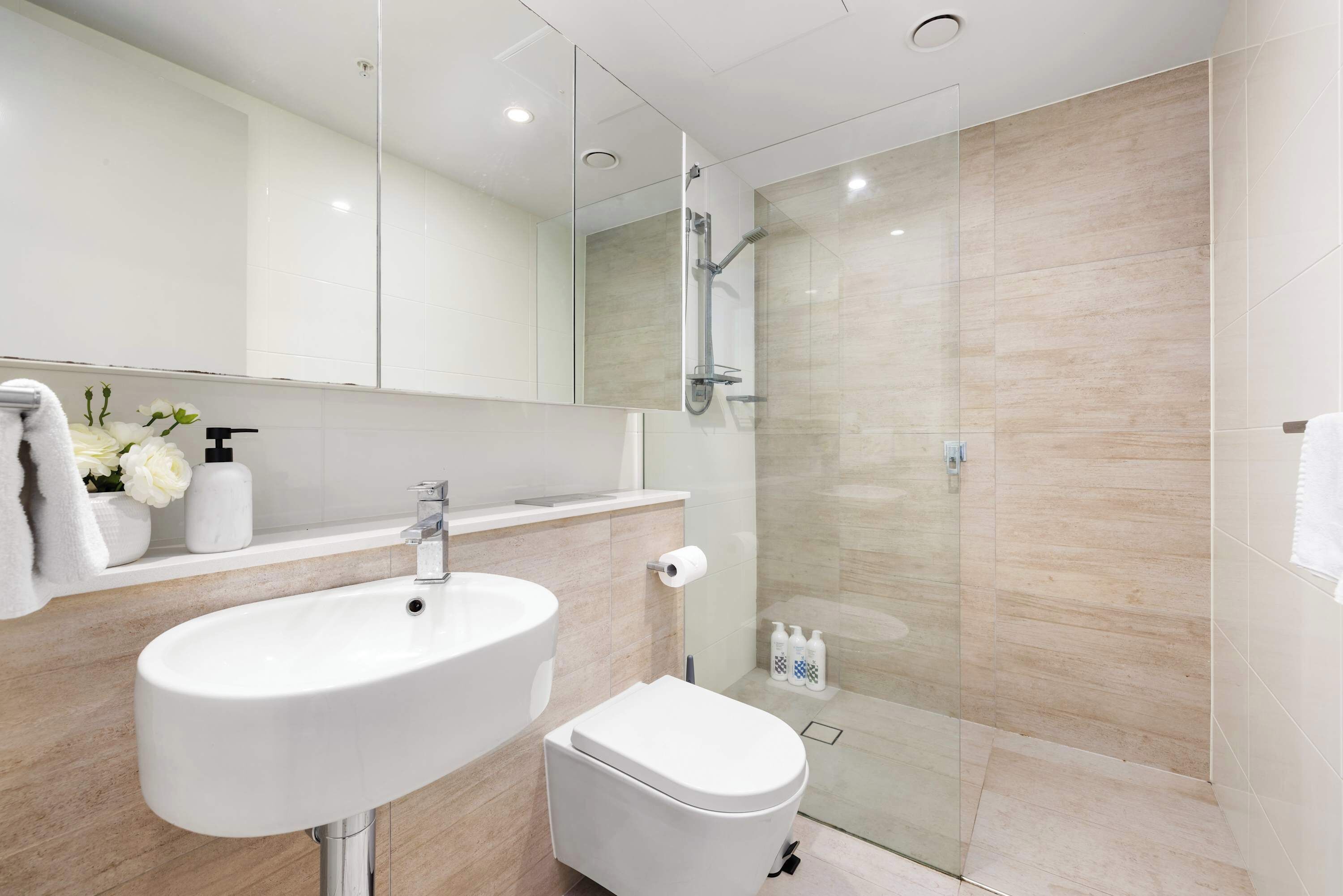 Une salle de bain moderne avec un lavabo, des toilettes et une douche à parois de verre.