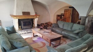 A cozy living room with a fireplace, green upholstered sofas, a wooden coffee table, and a patterned rug.