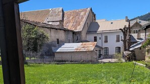 A grassy backyard with two wooden chairs, a stone pathway, and a metal fence.